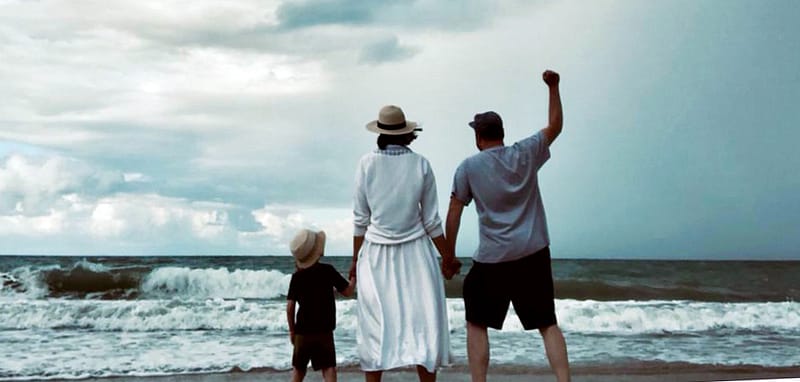 Eine Familie von hinten, die gemeinsam aufs Meer blickt – Symbol für Zusammenhalt und Aufbruch.